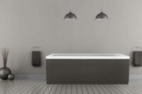 Idun badekar fra Interform med grå panelfarge. Grå tregulv og grå vegg. Svarte detaljer som lamper, håndduk og vasker.