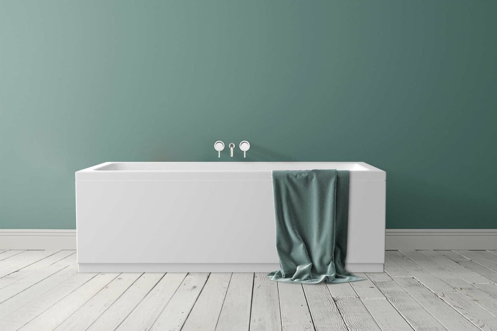 Idun badekar fra Interform. Nydelig grønn farge på vegg og rustikk gulv. Håndkle over badekarkant og armatur i krom.