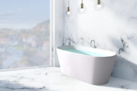 Urban frittstående kompositt badekar i hvit matt utførelse fra Interform med gulvarmatur i krom. Gulv og vegg i marmor. Utsikt mot boligstrøk.